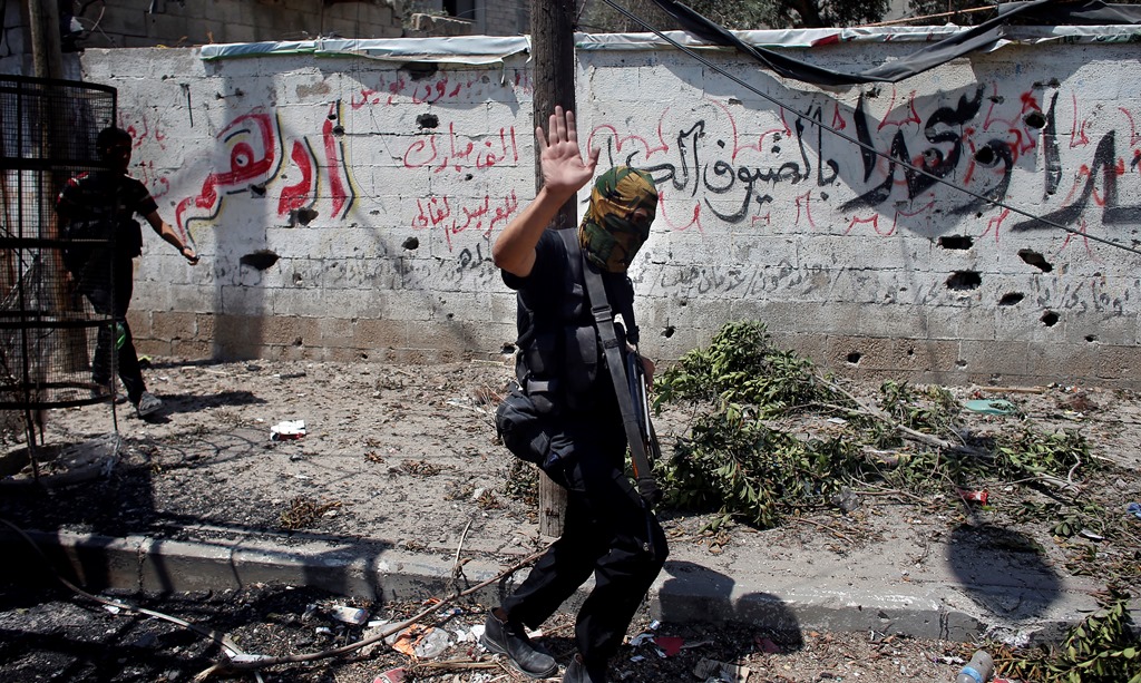 An armed Hamas militant walks in a street in Gaza's eastern Shejaiya district on July 20, 2014. At least 40 people were killed and nearly 400 wounded in Israeli shelling of Gaza's northeastern Shejaiya district overnight, medics said. AFP PHOTO / THOMAS COEX